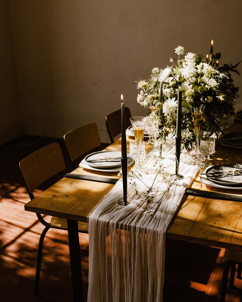 Elegant wedding table setting with candles and flowers on a long wooden table